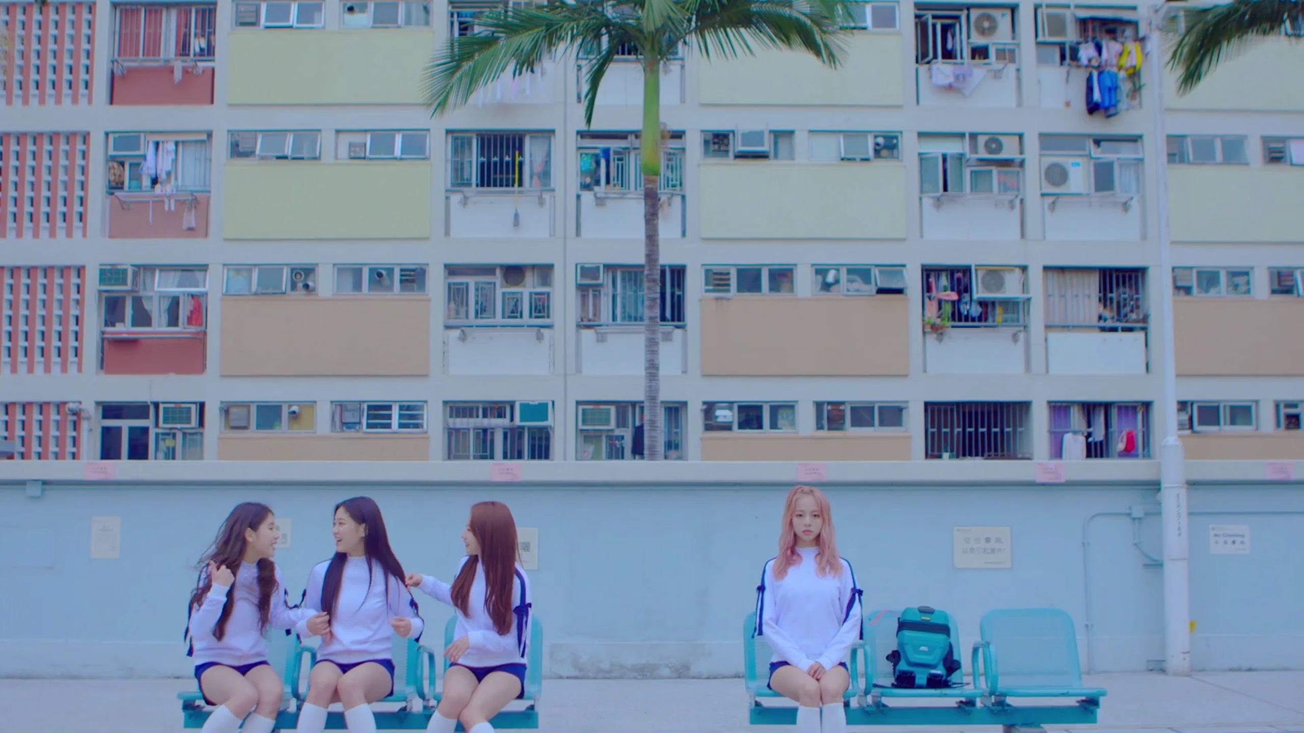 Loona One Third sitting on benches. Vivi sits separately from the rest of them.